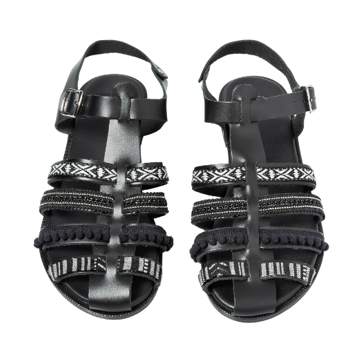 A black sandal featuring multiple straps with various textures and patterns, including a buckle strap around the ankle and decorative details on the upper straps.