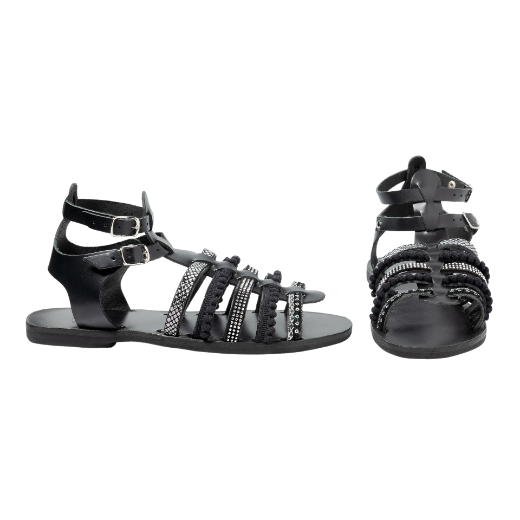 A black sandal with double buckle straps around the ankle and several upper straps adorned with different textures and embellishments.
