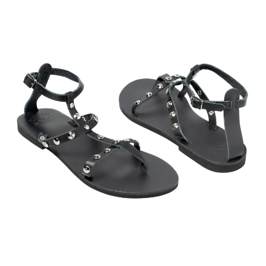 A black sandal featuring multiple thin straps, including one around the ankle and several on the upper foot, with metallic studs as embellishments.