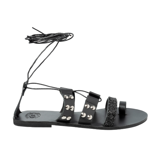A black sandal with a lace-up design, featuring multiple straps with studs and textured details on the upper foot and a toe loop.
