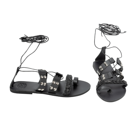 A black sandal with a lace-up design, featuring multiple straps with studs and textured details on the upper foot and a toe loop.