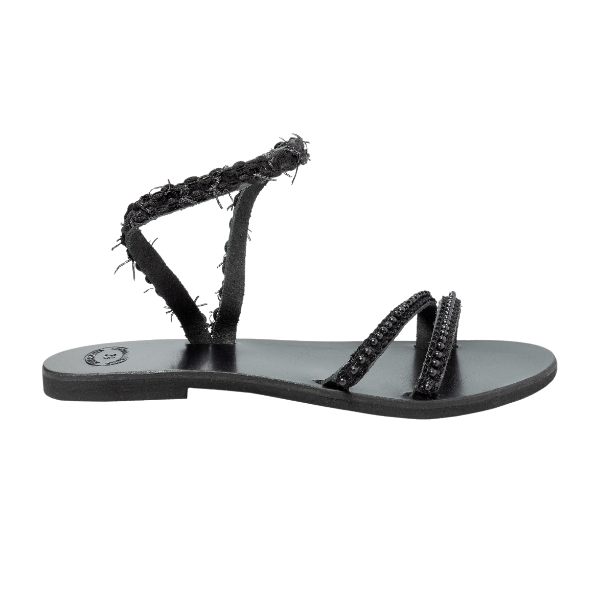 A black sandal with a single textured strap wrapping around the ankle and two thin upper straps, all featuring small decorative elements.